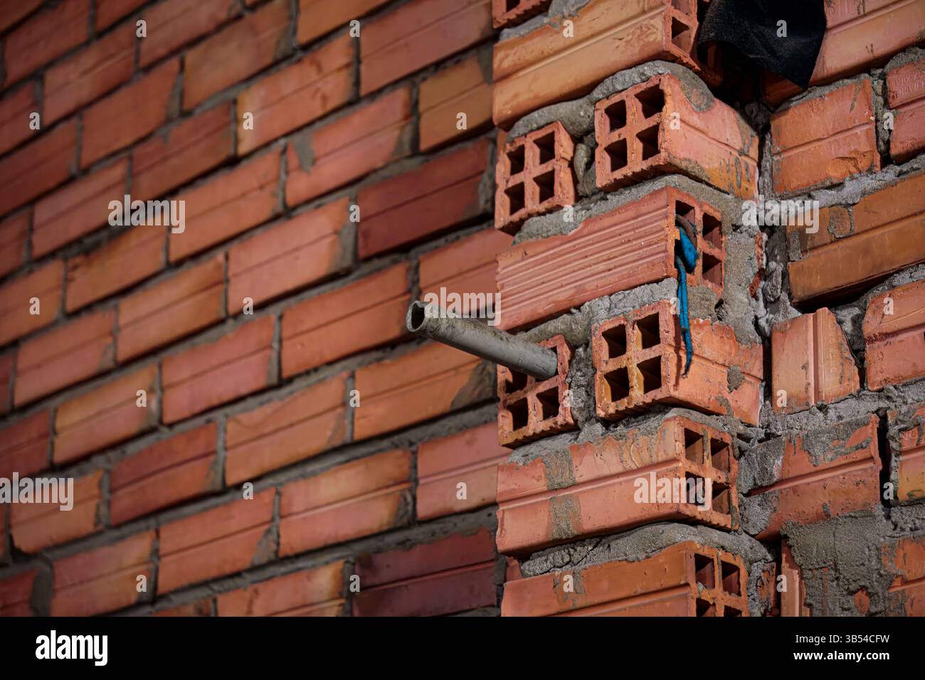 Mur creux en briques rouges en construction avec tuyau utilitaire Banque D'Images