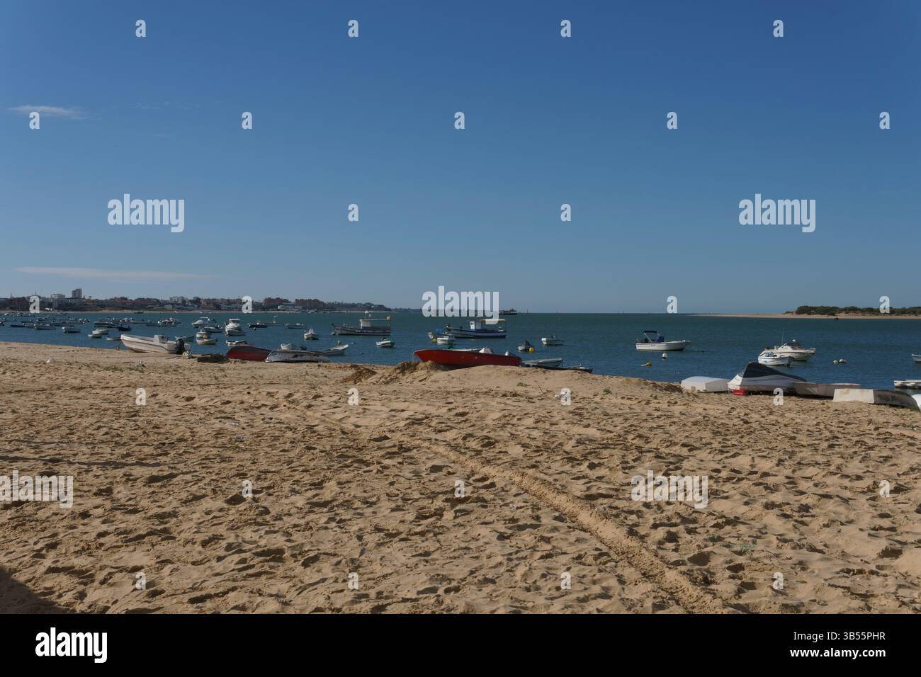 Journée ensoleillée à la plage avec des bateaux ancrés dans la mer tranquille Banque D'Images