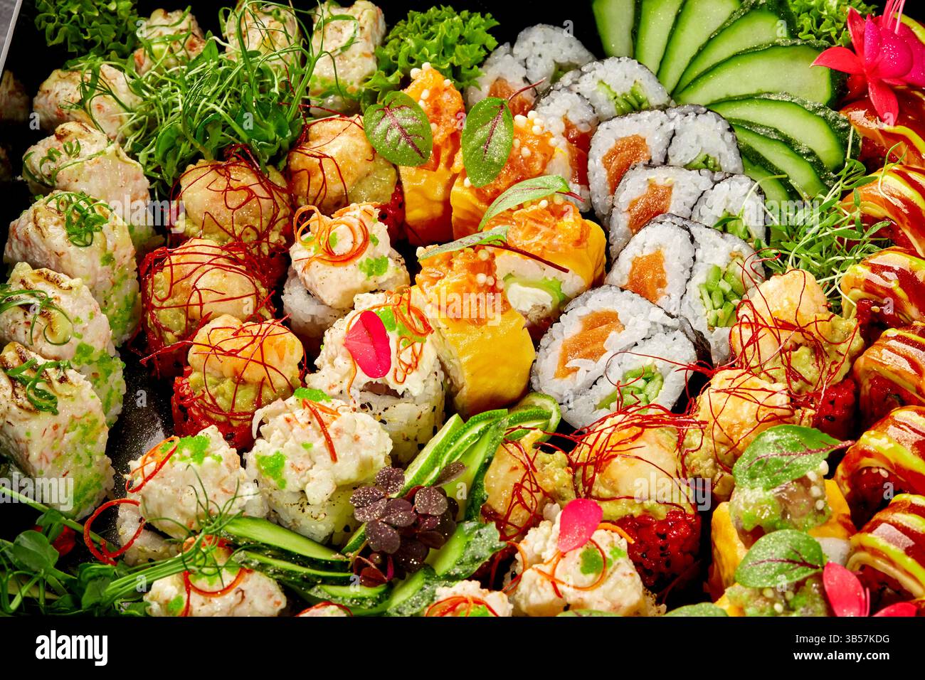 Assiette de sushis vibrante avec un assortiment de maki, uramaki et nigiri, garnie de légumes frais et de fleurs comestibles Banque D'Images