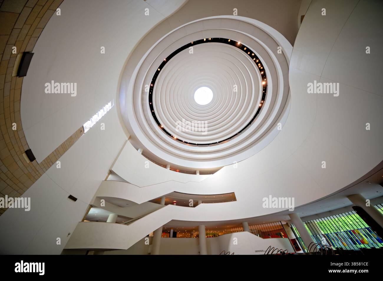WASHINGTON DC — le dôme distinctif au-dessus de l'atrium principal du Musée national des Indiens d'Amérique présente un design incurvé élégant qui permet à la lumière naturelle d'inonder l'espace central. Conçu par l'architecte pieds-Noirs Douglas Cardinal, le dôme intègre des principes de conception indigènes avec son oculus central orienté vers l'est et ses formes organiques fluides. Cette caractéristique architecturale de premier plan couronne l'espace de rassemblement central de 120 mètres de haut du musée connu sous le nom de Potomac, créant un point de convergence spectaculaire pour les visiteurs explorant l'un des bâtiments architecturaux les plus uniques du Smithsonian. Banque D'Images