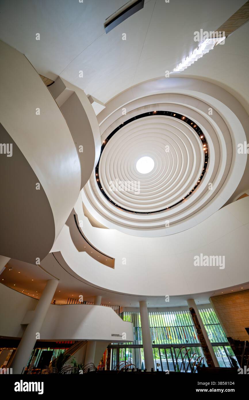 WASHINGTON DC — le dôme distinctif au-dessus de l'atrium principal du Musée national des Indiens d'Amérique présente un design incurvé élégant qui permet à la lumière naturelle d'inonder l'espace central. Conçu par l'architecte pieds-Noirs Douglas Cardinal, le dôme intègre des principes de conception indigènes avec son oculus central orienté vers l'est et ses formes organiques fluides. Cette caractéristique architecturale de premier plan couronne l'espace de rassemblement central de 120 mètres de haut du musée connu sous le nom de Potomac, créant un point de convergence spectaculaire pour les visiteurs explorant l'un des bâtiments architecturaux les plus uniques du Smithsonian. Banque D'Images