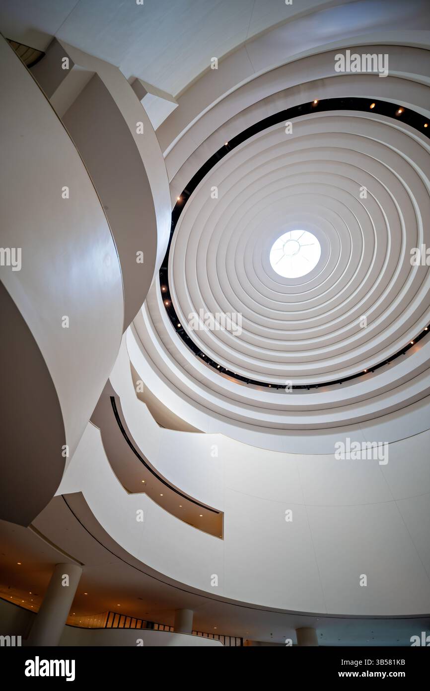 WASHINGTON DC — le dôme distinctif au-dessus de l'atrium principal du Musée national des Indiens d'Amérique présente un design incurvé élégant qui permet à la lumière naturelle d'inonder l'espace central. Conçu par l'architecte pieds-Noirs Douglas Cardinal, le dôme intègre des principes de conception indigènes avec son oculus central orienté vers l'est et ses formes organiques fluides. Cette caractéristique architecturale de premier plan couronne l'espace de rassemblement central de 120 mètres de haut du musée connu sous le nom de Potomac, créant un point de convergence spectaculaire pour les visiteurs explorant l'un des bâtiments architecturaux les plus uniques du Smithsonian. Banque D'Images