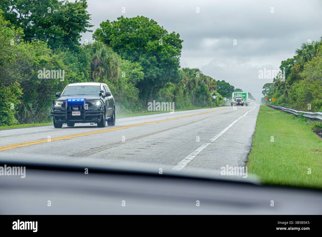 Palm Beach County Florida, Bee Line Highway route 710, large charge surdimensionnée approchant, 2 route à deux voies, avertissement de véhicule anticipé, escorte de police SUV, clignotant Banque D'Images