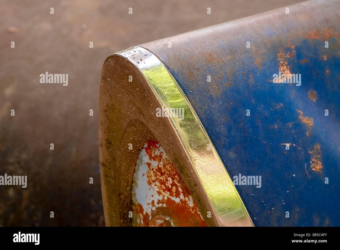 Gros plan d'un feu arrière rouillé de voiture de course classique avec peinture bleue et garniture chromée, montrant un style vintage et des détails automobiles altérés. Banque D'Images