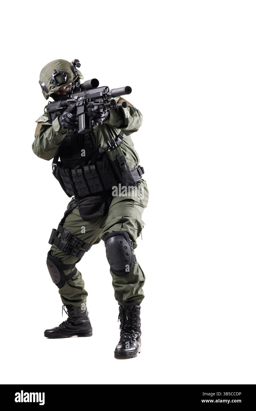 Un soldat tactique en uniforme complet, équipé d'un équipement de protection et d'une arme à feu, prêt et prêt avec une position professionnelle, isolé contre un nettoyage Banque D'Images