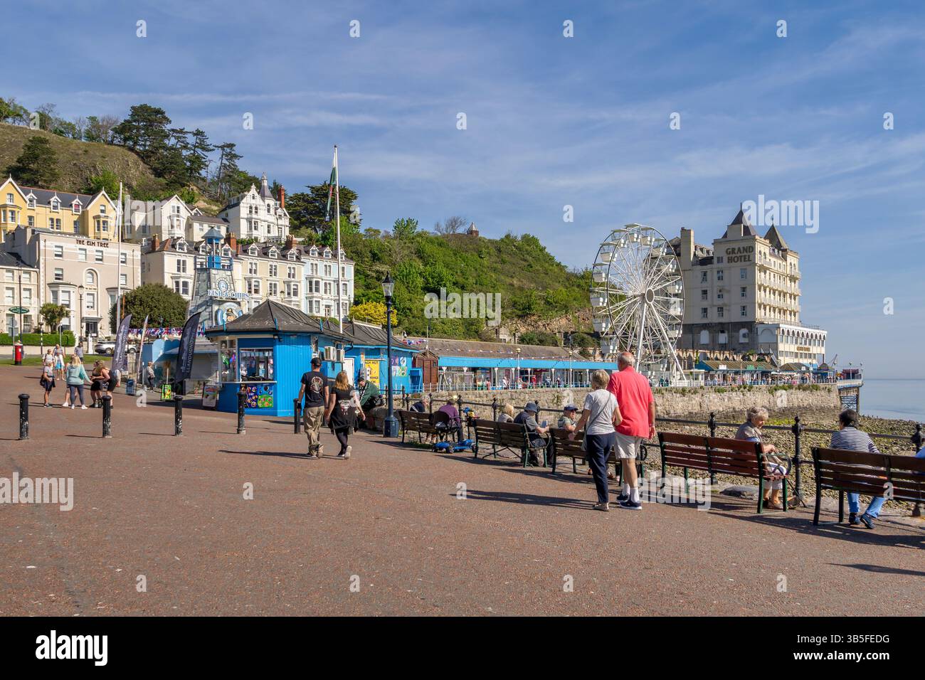 Llandudno Promenade avec la jetée, Grand Hôtel, Big Wheel, hôtels de bord de mer et les gens appréciant le temps chaud du printemps. Banque D'Images