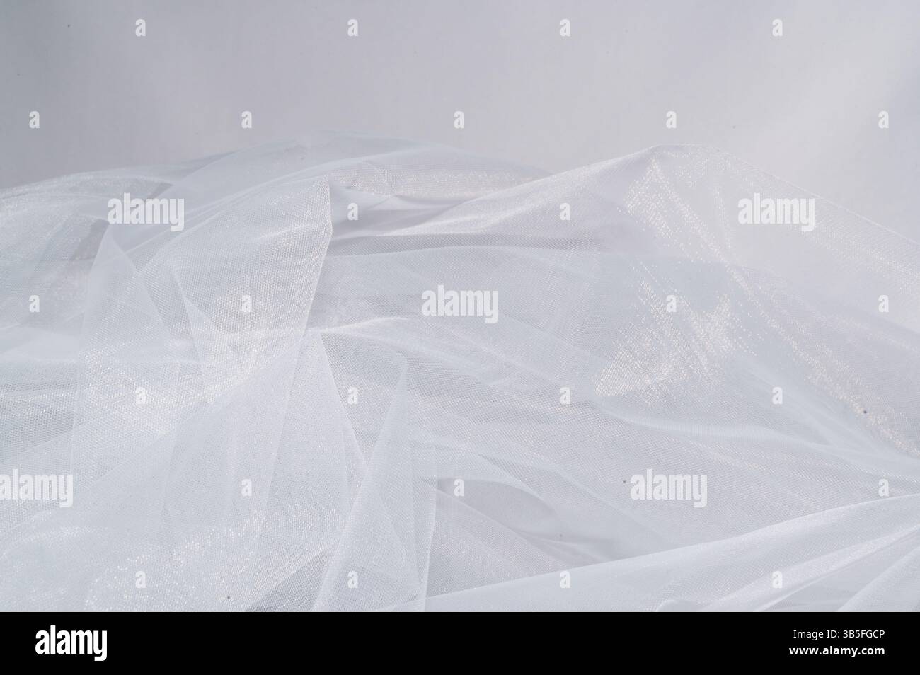 Il s'agit d'une image détaillée en gros plan présentant un beau morceau de tissu délicat en tulle blanc, soulignant sa texture et son élégance Banque D'Images