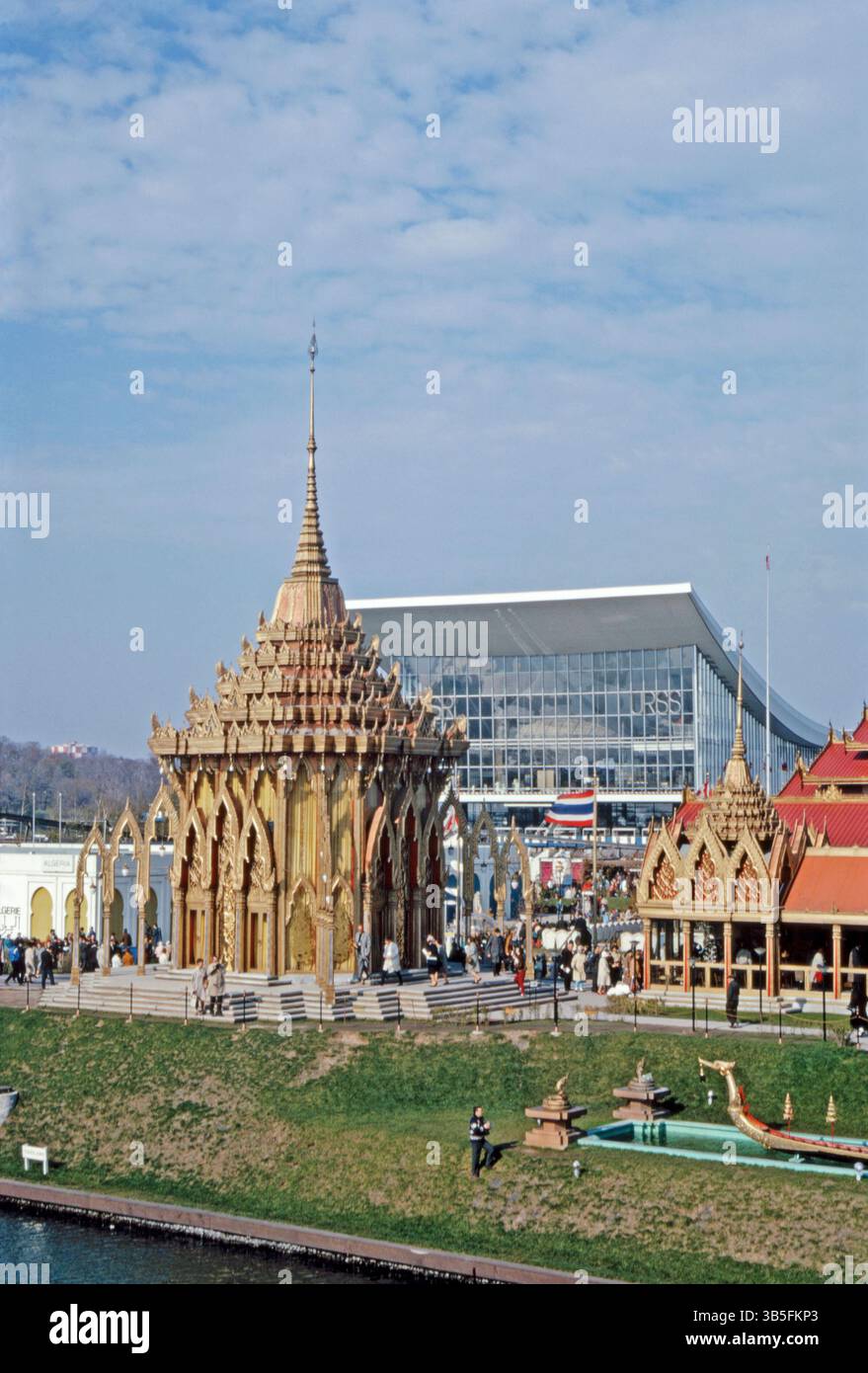 Le pavillon thaïlandais à Expo 67, Montréal, Québec, Canada en 1967. La pièce maîtresse du pavillon thaïlandais était une réplique d'un sanctuaire bouddhiste du XVIIIe siècle. Le bâtiment orné a été bruni de laque rouge, verte et bleue et son haut toit ressemblant à une pagode surmonté d'une flèche haute et délicate, a été recouvert de tuiles dorées. Le pavillon russe est en arrière-plan – une photographie vintage des années 1960. Banque D'Images