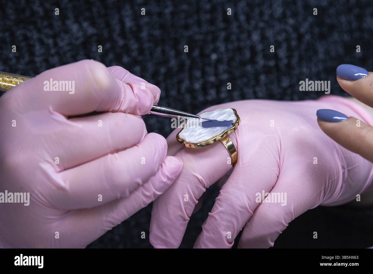 Technicien en ongles utilisant l'anneau comme palette pour vernis à ongles, détail tiré dans le salon Banque D'Images