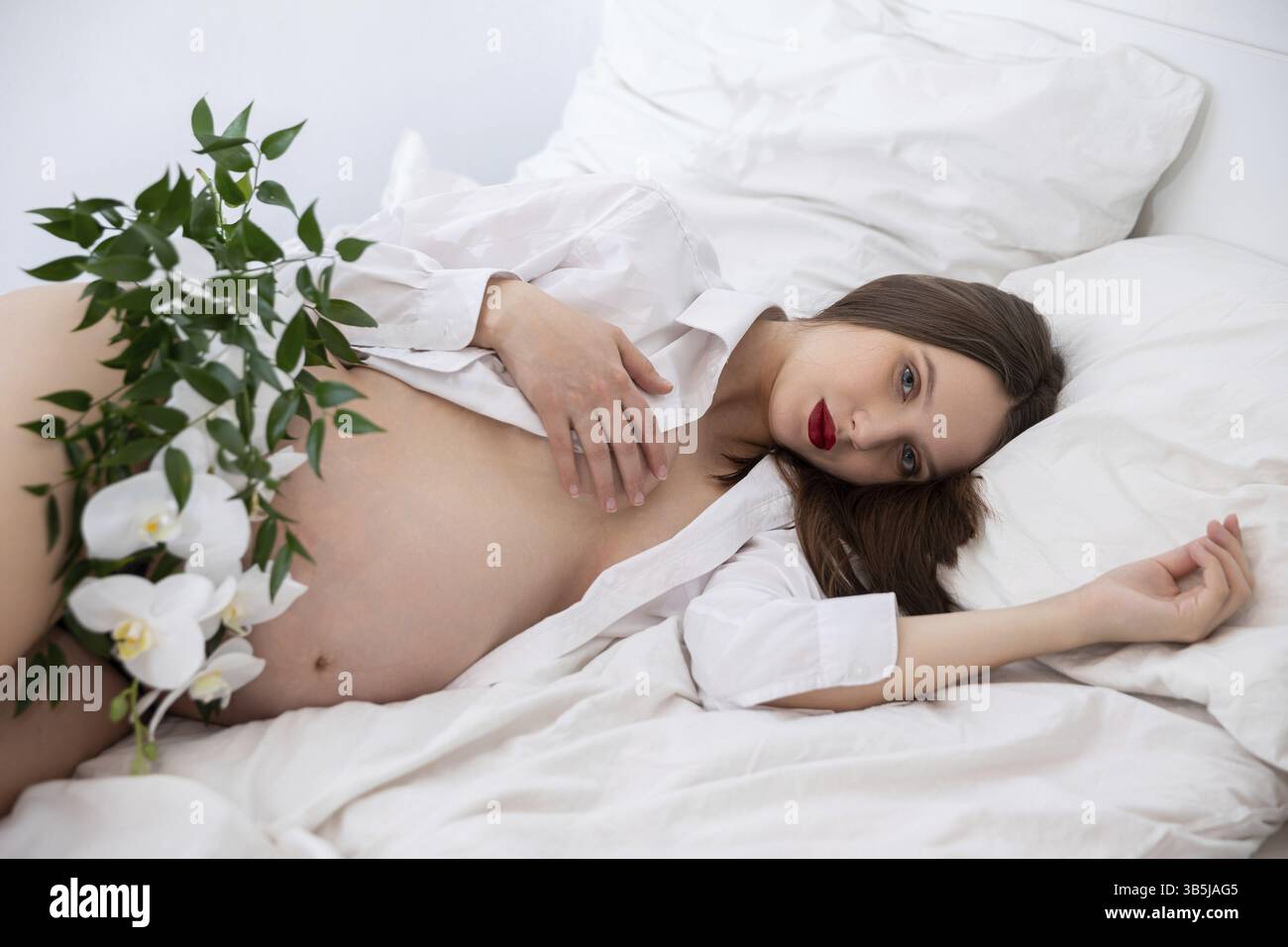 Une pose de maternité sereine avec des éléments naturels et une literie douce, célébrant l'essence de la maternité Banque D'Images