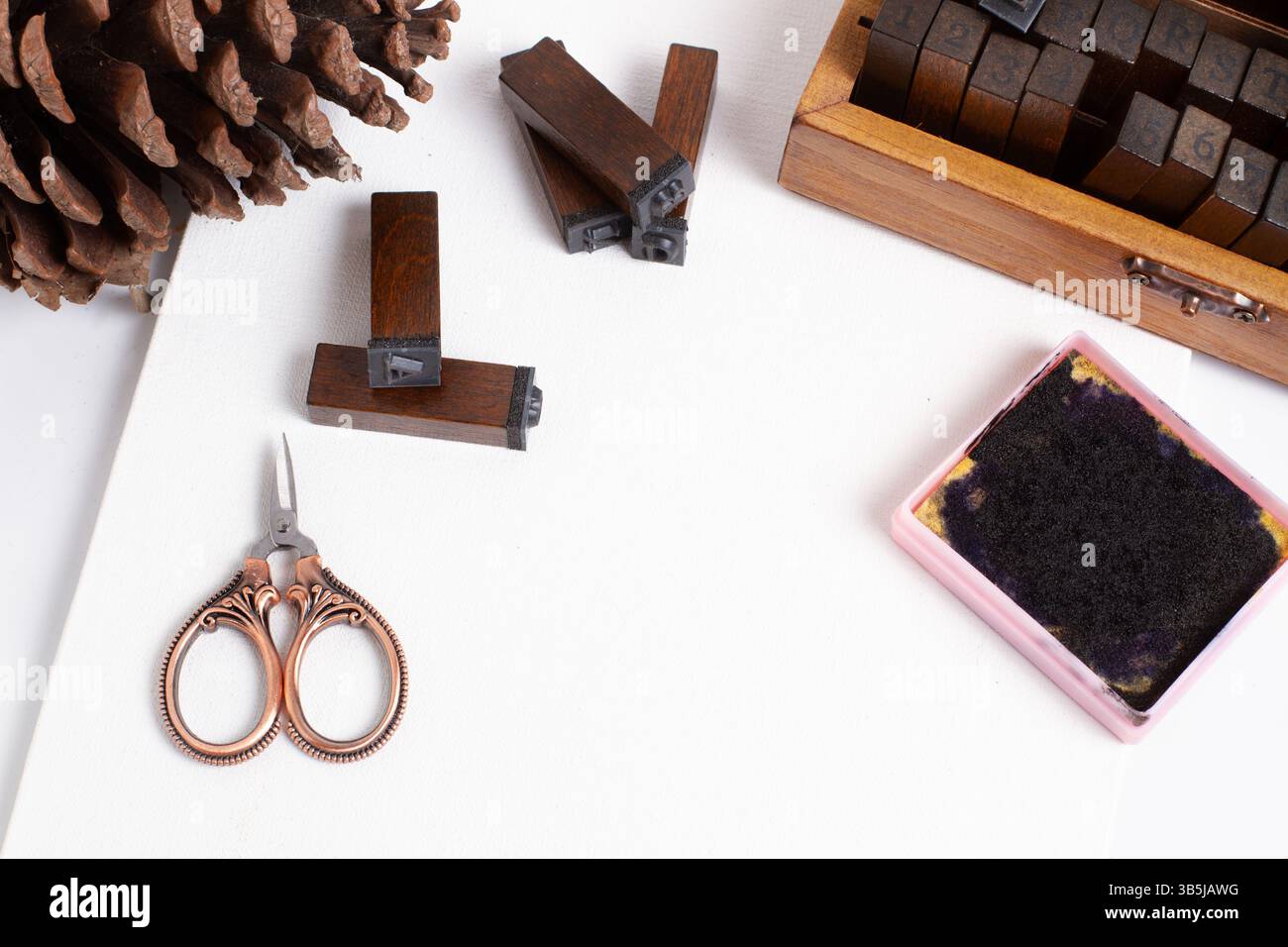 Timbres, tampon encreur, un petit ciseau et une pomme de pin sur une feuille de papier blanche dans une vue de dessus Banque D'Images