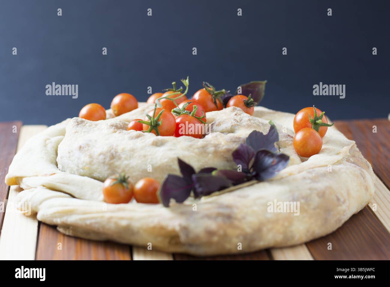 Tarte filo spiral burek avec tomates cerises sur table en bois Banque D'Images