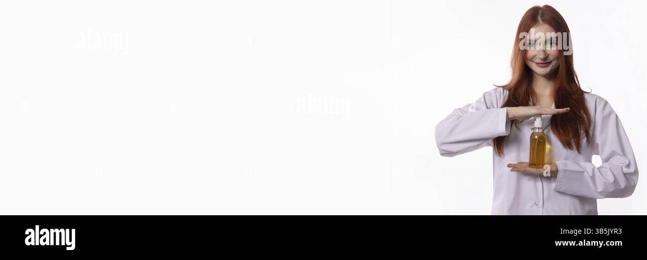 Une femme en blouse de laboratoire présentant une bouteille d'huile, symbolisant la recherche scientifique et les produits naturels Banque D'Images