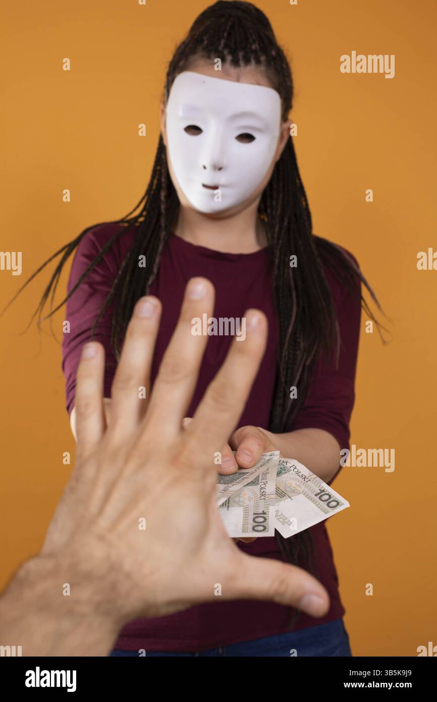 La main masculine prend de l'argent à un étranger qui a un masque partout sur son visage afin que personne ne le reconnaisse. De l'argent promis dans un prêt anonyme Banque D'Images