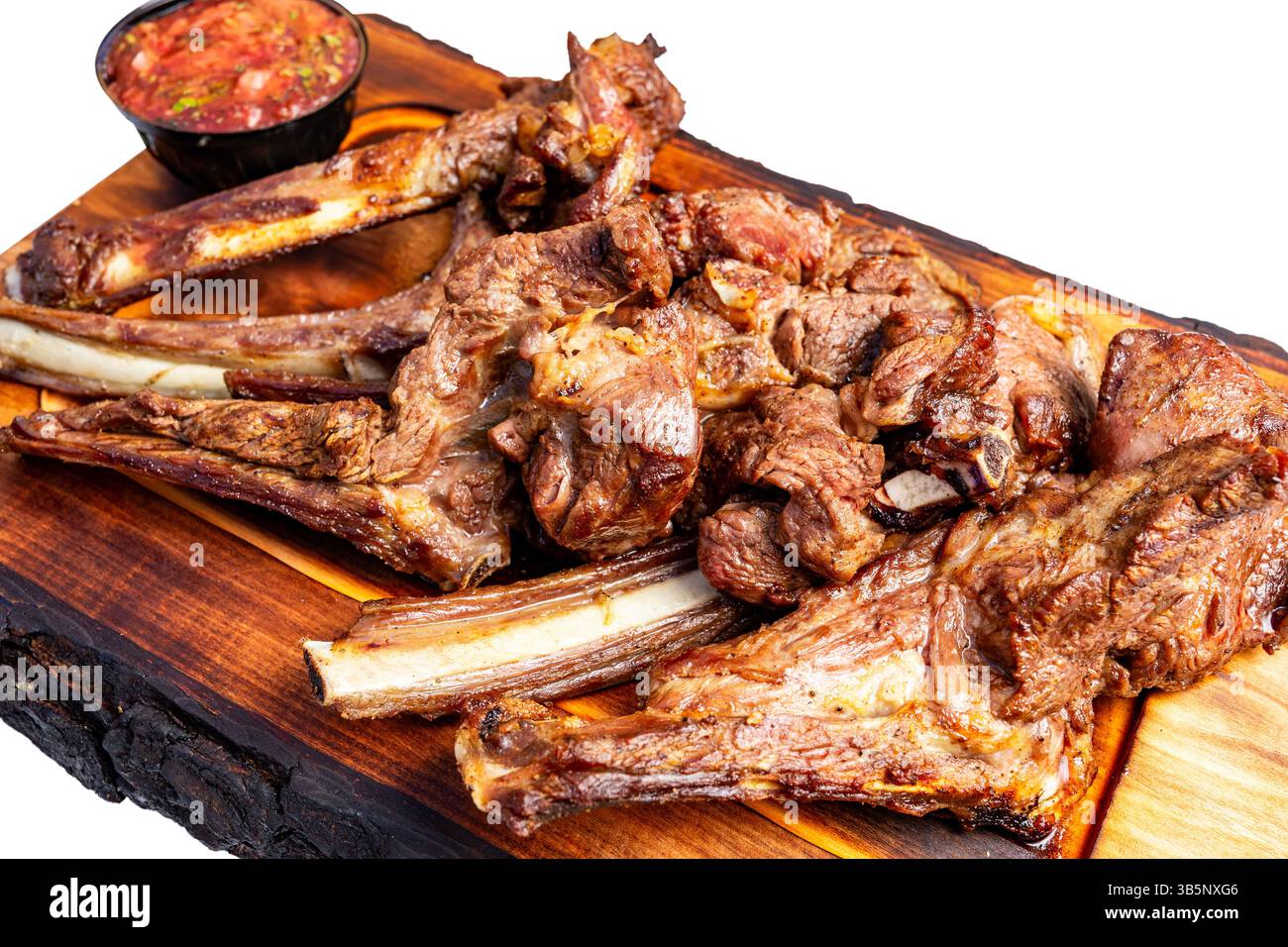 De succulentes côtes de porc grillées sont magnifiquement disposées sur un plateau en bois, accompagnées d'une salsa fraîche. Le plat met en valeur une idée de présentation vibrante Banque D'Images