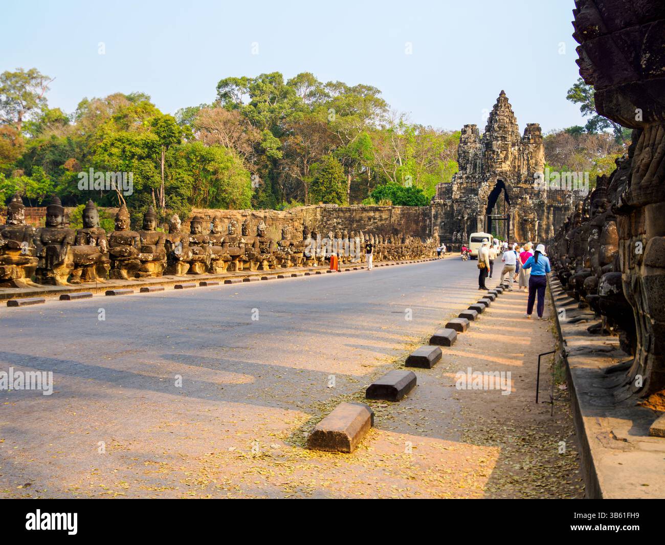 Les touristes traversent la chaussée pour entrer dans le complexe du temple Angkor Thom, Siem Reap, Cambodge Banque D'Images