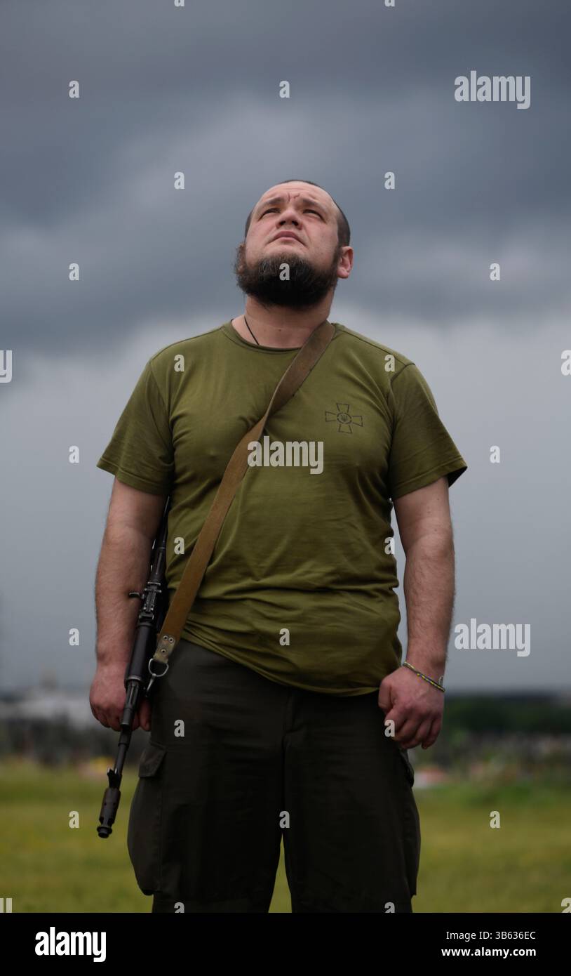 24 juin 2022, Kharkiv, Ukraine : un jeune soldat, regarde vers le ciel pour des réponses aux funérailles de son ami, à la périphérie de la ville de Kharkov au cimetière 18. C’est sur le héros de la course spatiale soviétique Y. Gagarine rue, Forces armées de l’Ukraine a déjà enterré plus de 100 soldats locaux, qui sont tombés devant les troupes russes sont enterrés. Comme auparavant avec l'Union soviétique, ils ont toujours souffert des attaques de guerre de la Russie, et le cimetière 18 met en valeur cette relation asymétrique. Les pierres tombales des combattants qui sont morts lors de l'attaque menée par Poutine dans le Donbass, il y a des années. À côté des morts d'hier sont Banque D'Images