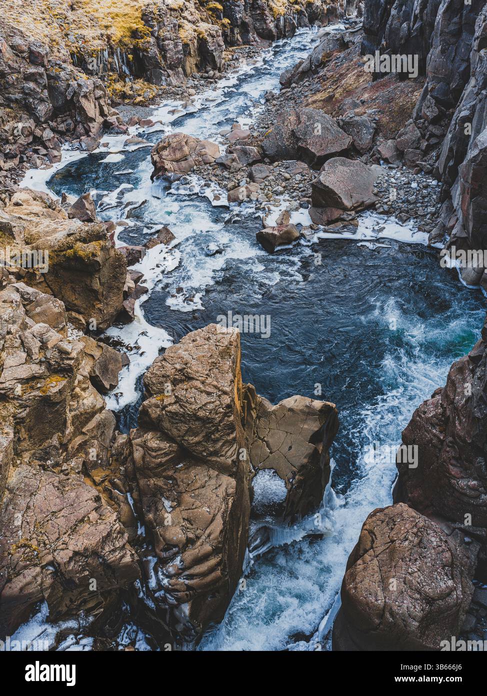 Rivière glaciaire sinueuse dans une gorge rocheuse près de la cascade Hengifoss, dans l'est de l'Islande Banque D'Images