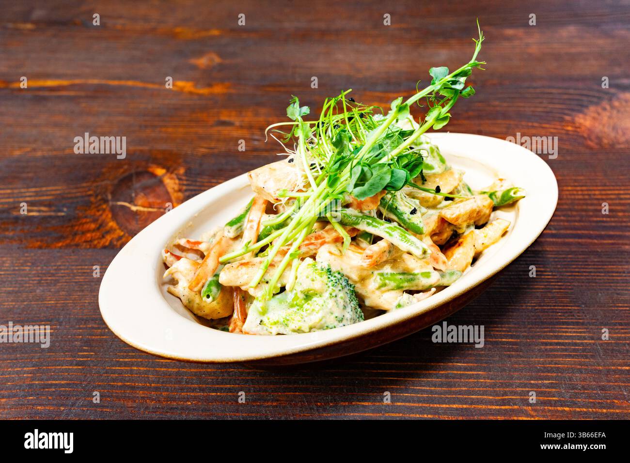 Un plat vibrant avec un assortiment de légumes frais dans une sauce crémeuse. La présentation met en valeur des ingrédients colorés garnis de p Banque D'Images