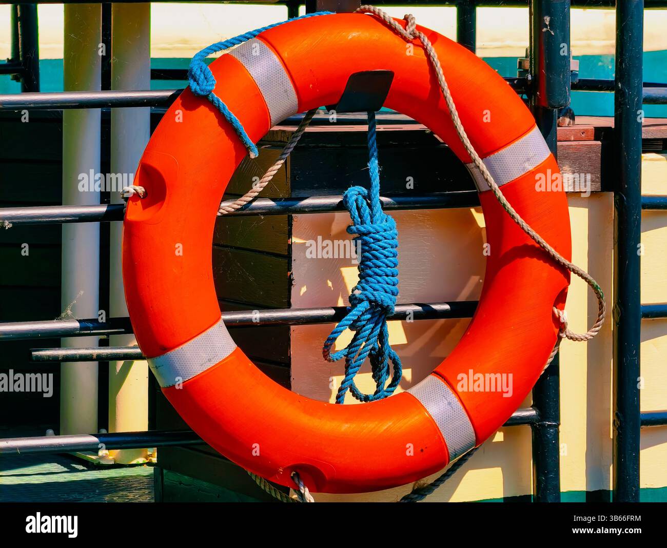 Anneau de bouée de sauvetage orange vif sur les garde-corps des navires – équipement de sécurité maritime pour les thèmes nautiques et côtiers. Banque D'Images