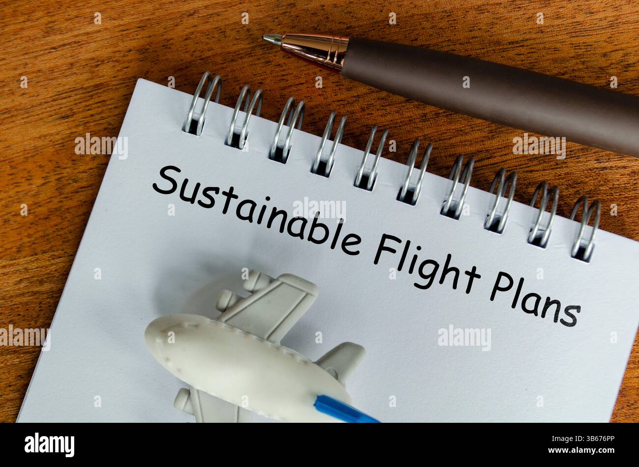 Texte de plans de vol durable sur bloc-notes blanc avec petit avion et fond de stylo. Sensibilisation à l'environnement. Banque D'Images