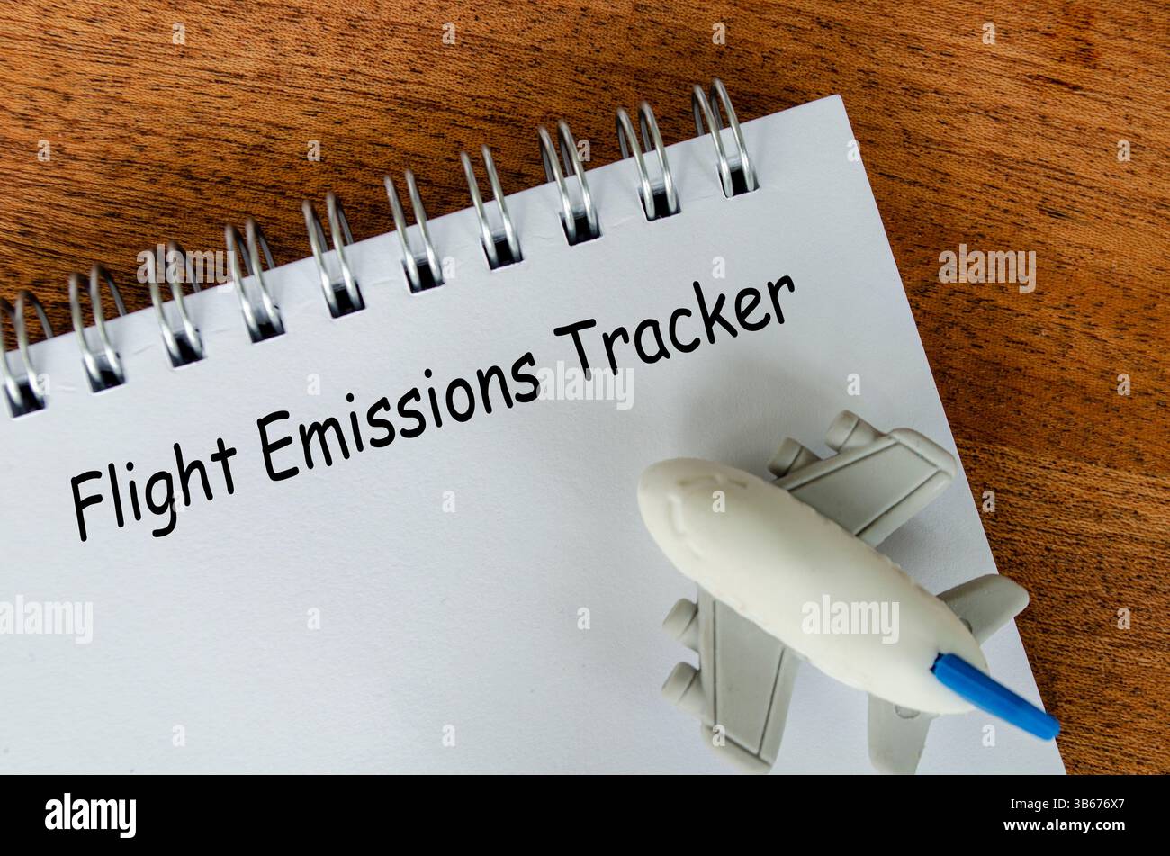 Texte de suivi des émissions de vol sur bloc-notes blanc avec petit fond d'avion. Sensibilisation à l'environnement Banque D'Images