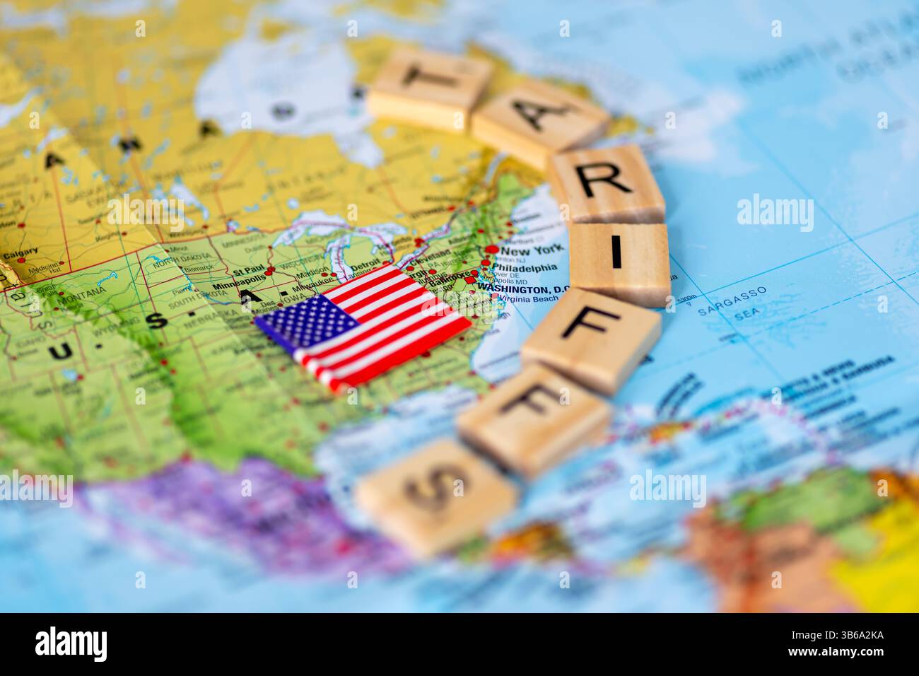 Une carte des États-Unis d'Amérique et le drapeau américain avec des carreaux de bois de lettre formant le mot tarifs. Un concept de tarifs américains. Banque D'Images