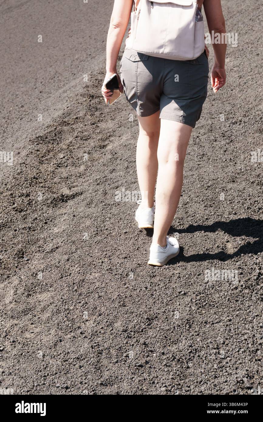 Personne randonnée sur les cendres volcaniques avec sac à dos et téléphone à la main Banque D'Images