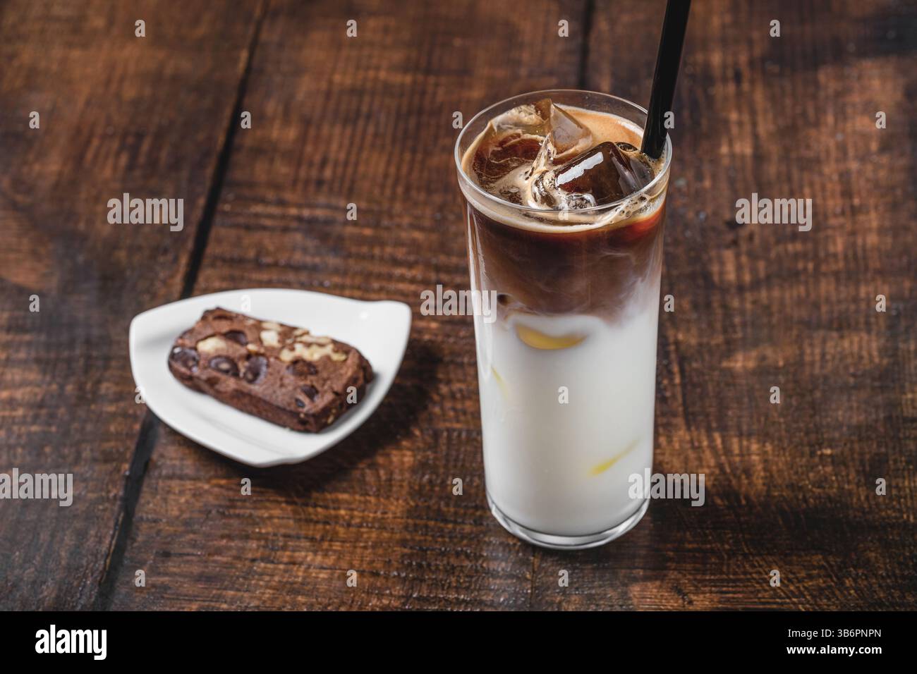 Grand verre rempli de glace, avec du café glacé mélangé à de la crème sur une table en bois Banque D'Images
