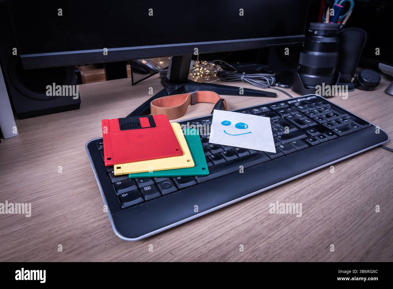 Disquettes colorées et une note smiley posée sur un clavier rétro, évoquant la technologie vintage et des souvenirs du passé Banque D'Images