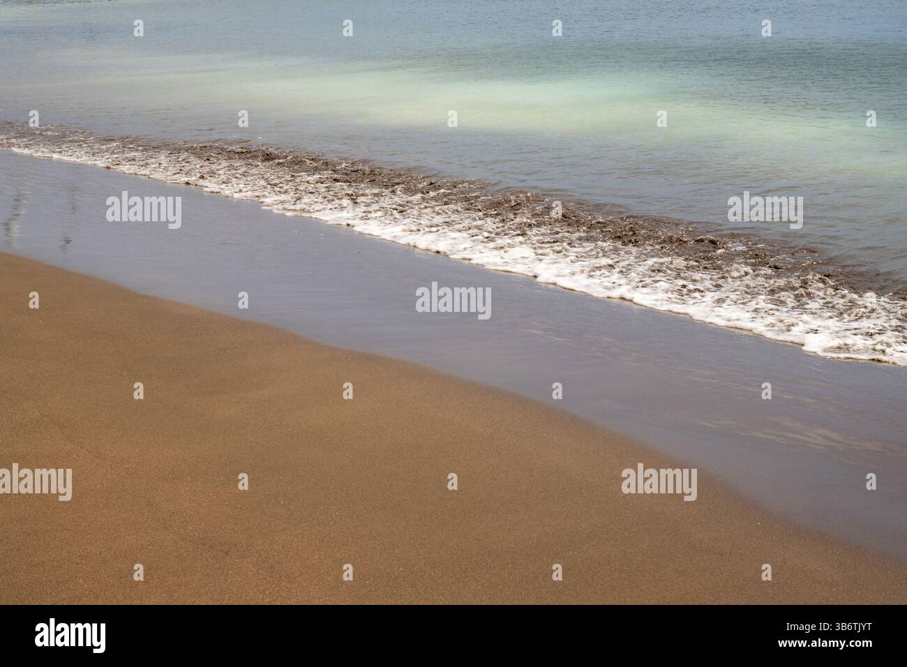 Plage de sable avec ligne de marée. Sable jaune, bleu clair et turquoise océan Atlantique. Taliarte, Las Palmas, Grande Canarie, Îles Canaries, Espagne. Banque D'Images
