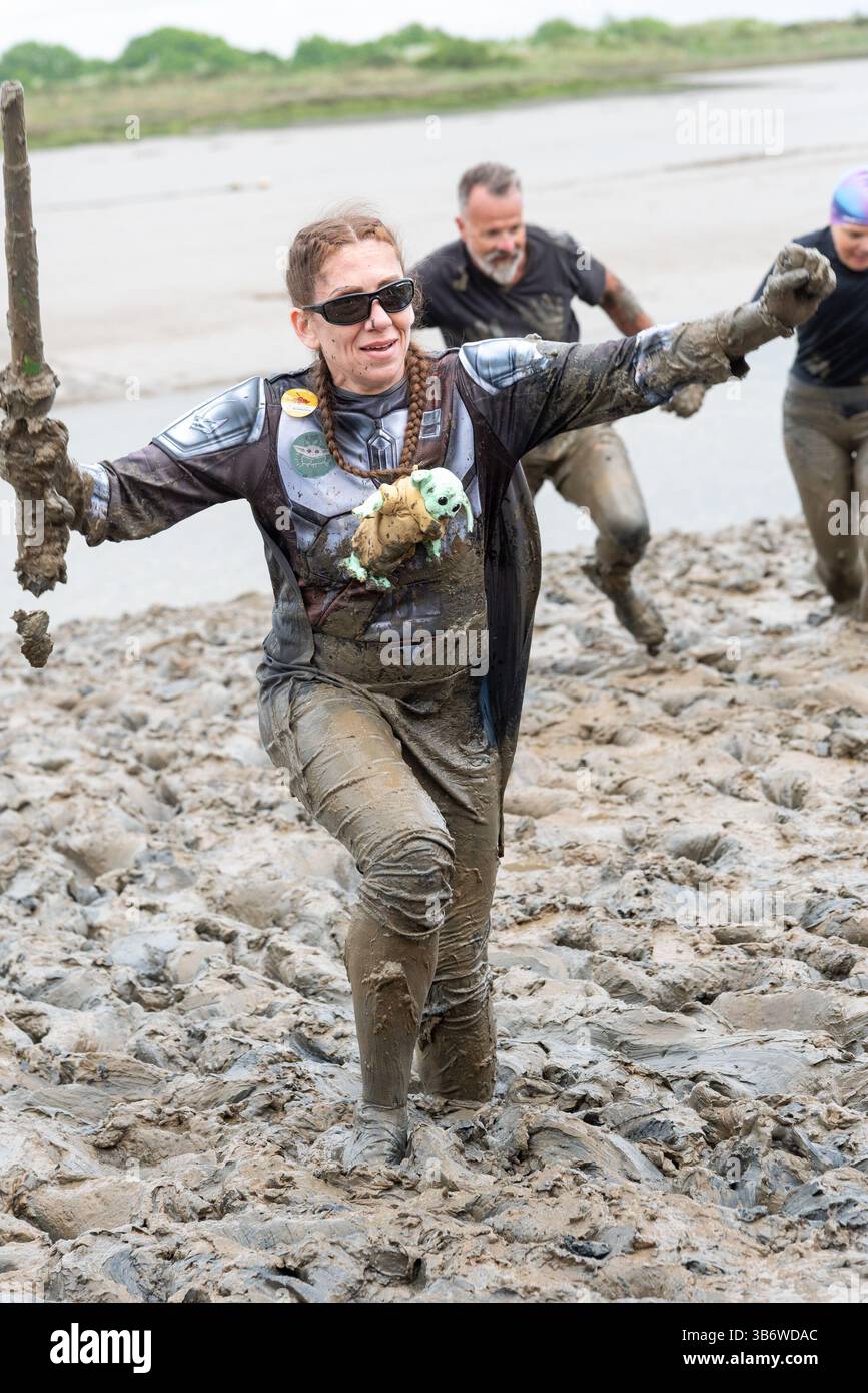 Promenade Park, Maldon, Essex, Royaume-Uni. 4 mai 2025. Un grand nombre de coureurs se sont attaqués au parcours épuisant qui les a emmenés à travers la rivière Chelmer et de retour à marée basse, à travers la boue glissante et accrocheuse. Les concurrents de Maldon Mud Race courent pour la charité, avec beaucoup en robe de fantaisie et tous se couvrent de la boue visqueuse pendant la course, en particulier ceux qui sont plus en arrière une fois que la boue est barattée. Femme en costume Star Wars Banque D'Images