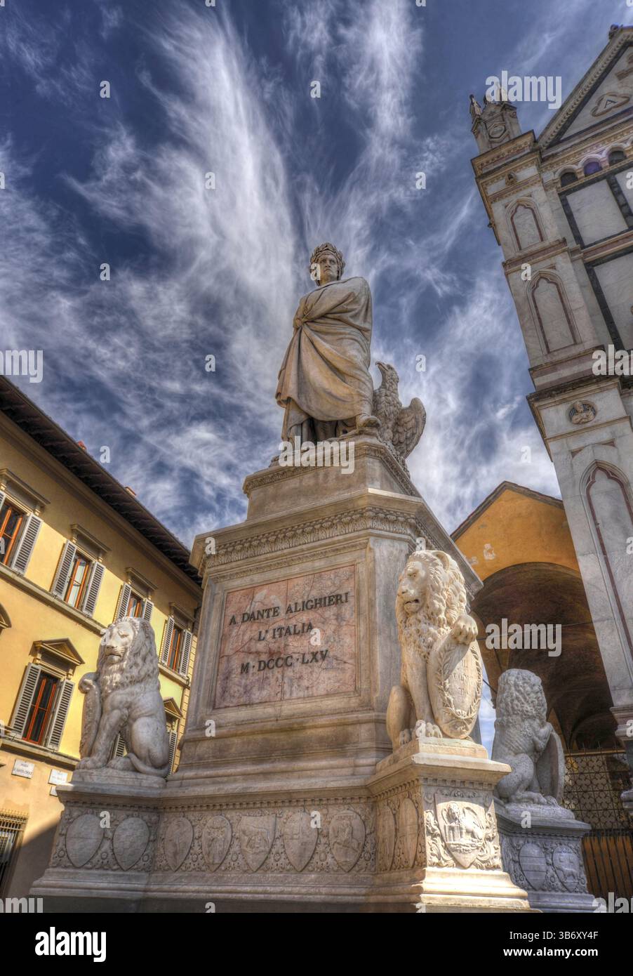 Statue de Dante Alighieri à Florence, en Italie, debout fièrement devant la Basilique di Santa Croce, sous un ciel dramatique avec des nuages sinueux. Banque D'Images