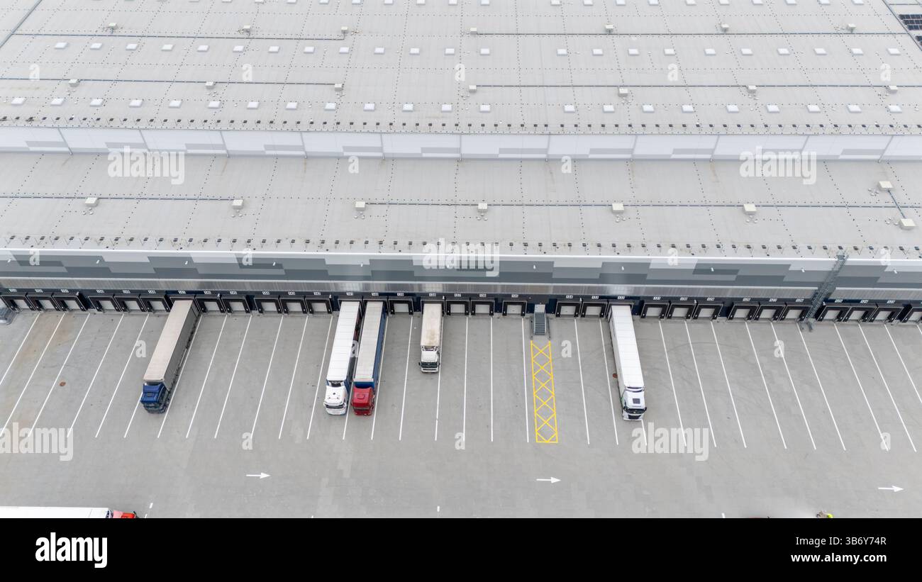Vue aérienne d'un grand entrepôt avec quais de chargement et camions stationnés. Banque D'Images