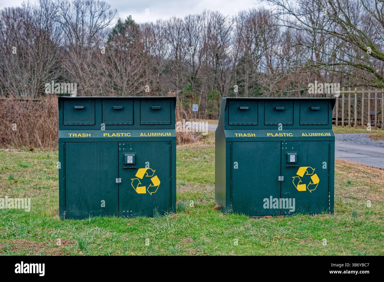Une paire de grandes poubelles en métal portent la preuve de l'environnement dans un parc avec des compartiments pour les déchets en plastique et en aluminium montrant le symbole recyclable Banque D'Images Une paire de grandes poubelles en métal portent la preuve de l'environnement dans un parc avec des compartiments pour les déchets en plastique et en aluminium montrant le symbole recyclable Banque D'Images