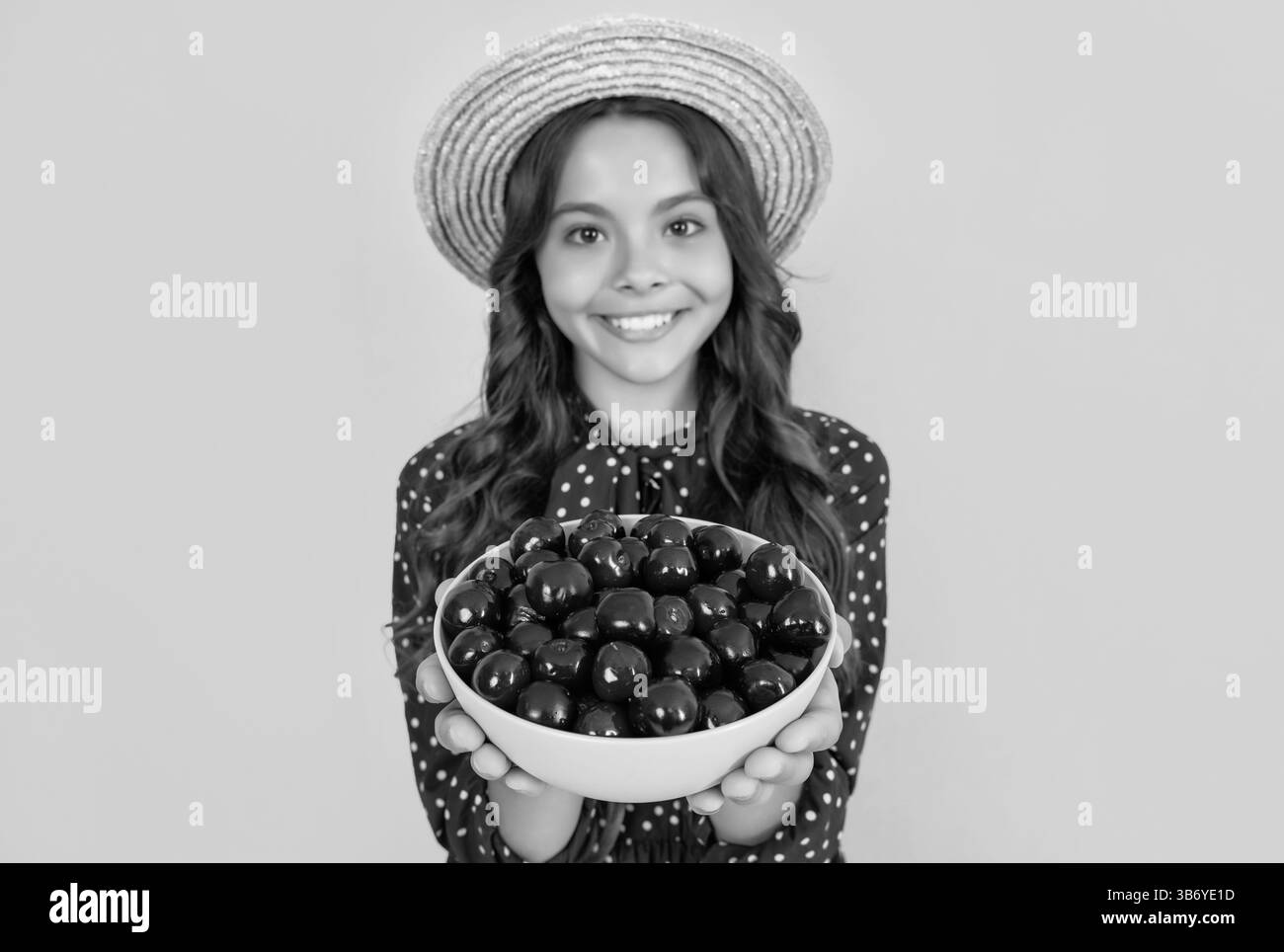 mise au point sélective de l'enfant heureux de l'adolescence tenir bol de cerise sur fond jaune Banque D'Images
