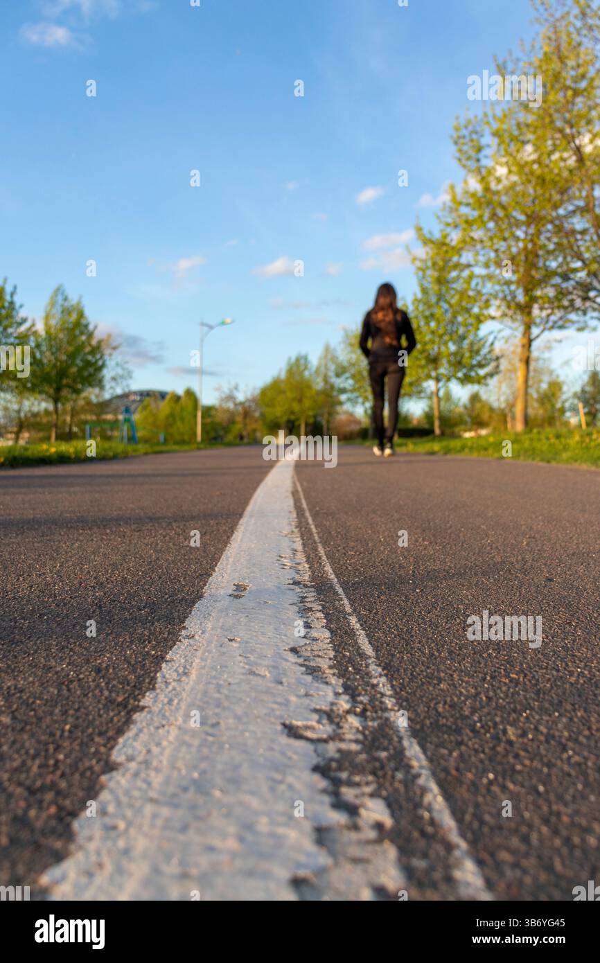Surface asphaltée de la piste de jogging avec voie de séparation peinte. Femme marchant Banque D'Images