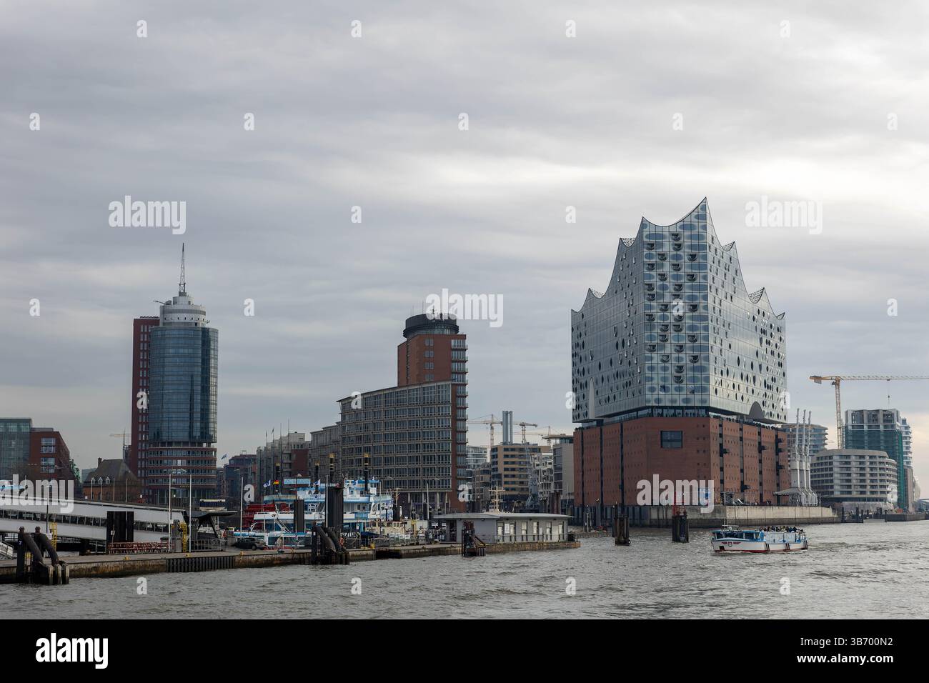 Des structures architecturales bordent le front de mer de Hambourg, mettant en valeur un mélange de styles moderne et traditionnel. Un ciel nuageux projette une lumière tamisée sur le b. Banque D'Images