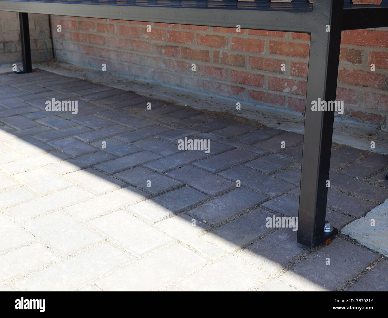 bancs en métal noir avec sièges à lattes et dossiers ancrés à des pavés de briques près de briques rouges dans un motif de maçonnerie traditionnel avec une vue rapprochée de th Banque D'Images bancs en métal noir avec sièges à lattes et dossiers ancrés à des pavés de briques près de briques rouges dans un motif de maçonnerie traditionnel avec une vue rapprochée de th Banque D'Images