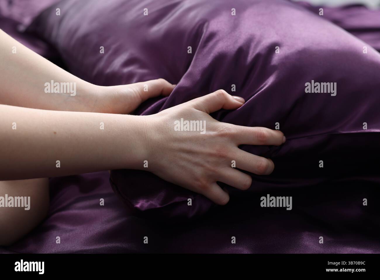 Femme avec oreiller sur linge de lit en soie, gros plan Banque D'Images