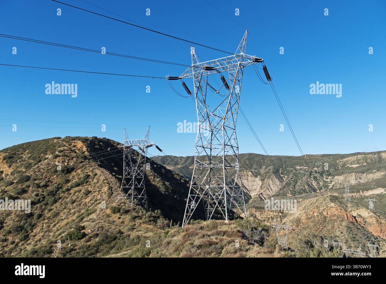 Lignes de transport électrique à haute tension et tours traversant un col dans les montagnes de Liebre Banque D'Images
