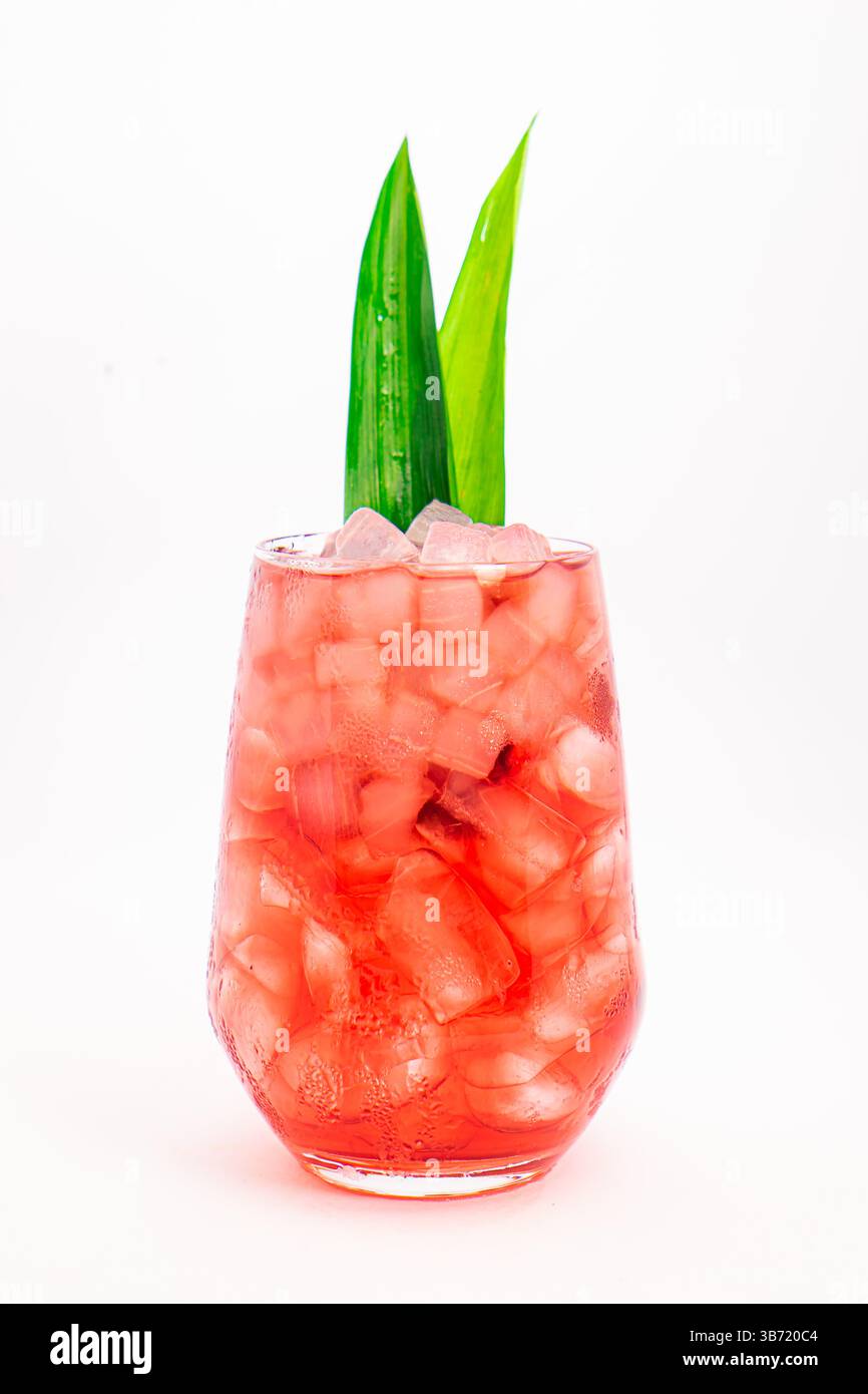 cocktail de baies rouges servi dans un verre clair avec de la glace pilée et des feuilles tropicales vertes isolées sur fond blanc. Photo de haute qualité Banque D'Images