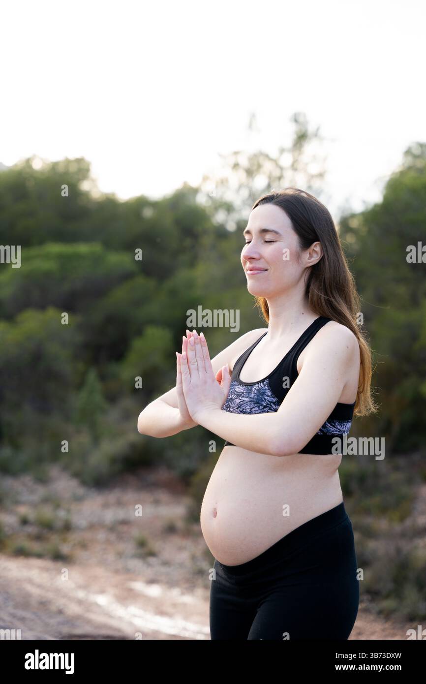 Femme enceinte profitant de l'air frais avec les mains sur le ventre Banque D'Images