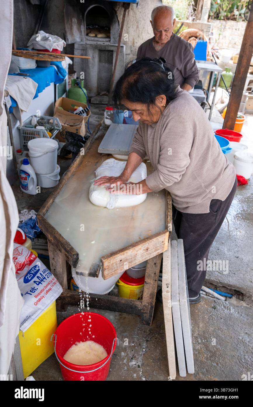 Un couple d'aînés fabriquant du fromage Feta de manière traditionnelle en utilisant uniquement du lait de brebis. - Korucam (Kormakiti) village maronite - Chypre du Nord. Banque D'Images