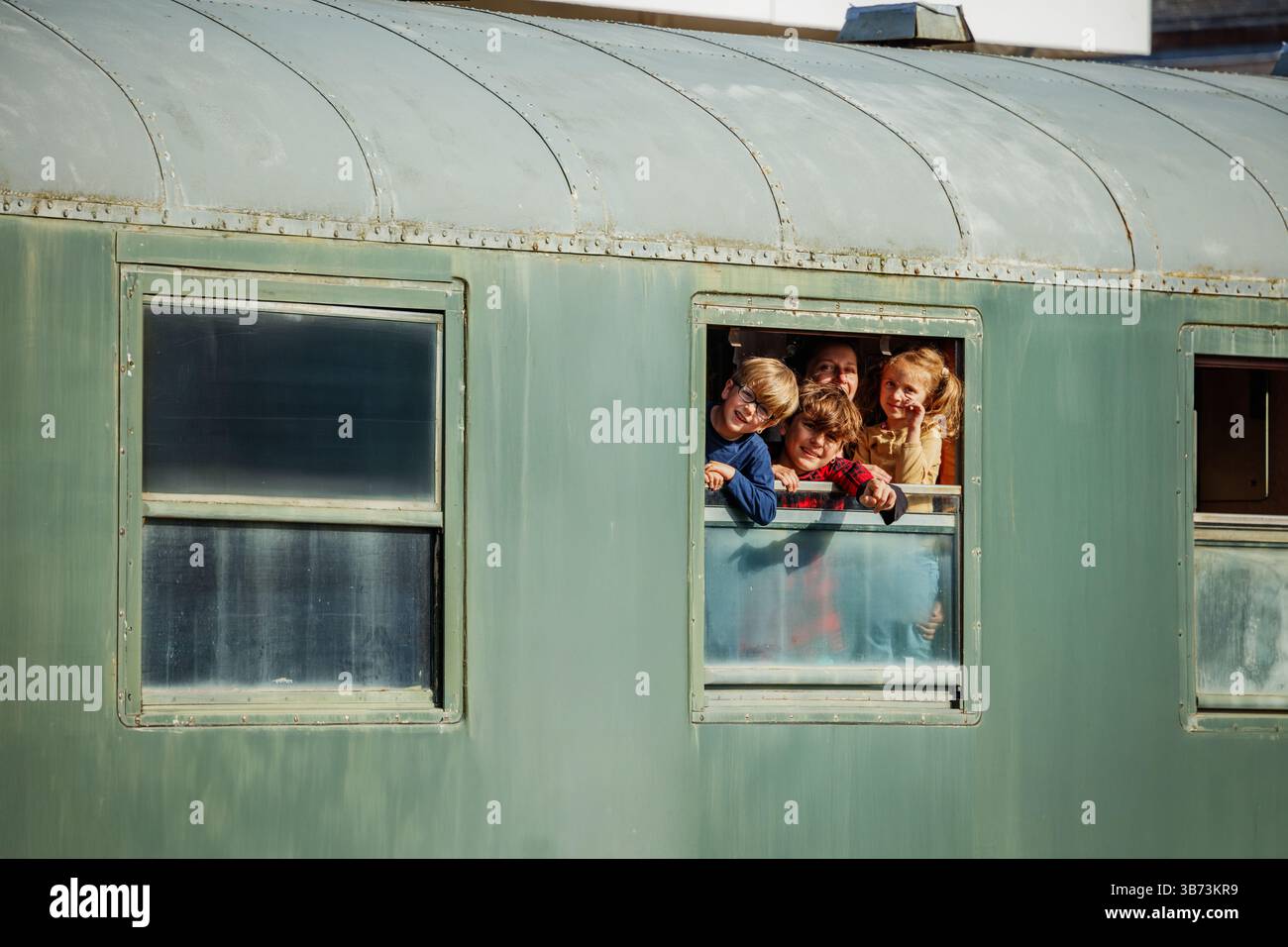 Deux enfants brandissent la fenêtre du train dans la lumière chaude de la fin de l'après-midi Banque D'Images