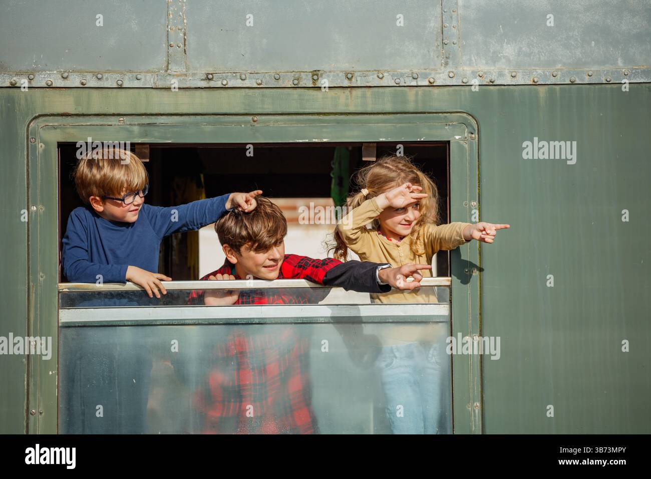 Les enfants regardent depuis la fenêtre du chariot en faisant des gestes sur la scène à l'extérieur Banque D'Images