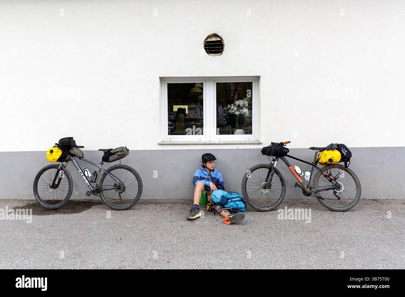 Touriste sur un voyage de vélo, bikepacking de Ljubljana à Piran en Slovénie, se détendre sur un trottoir dans une petite ville de vrhnika Banque D'Images