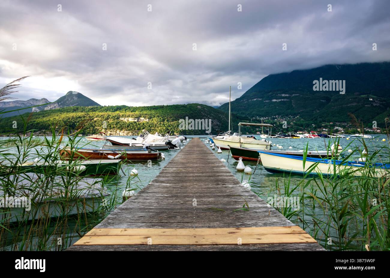 Jetée en bois s'étendant dans le lac d'Annecy avec vue sur la montagne Banque D'Images