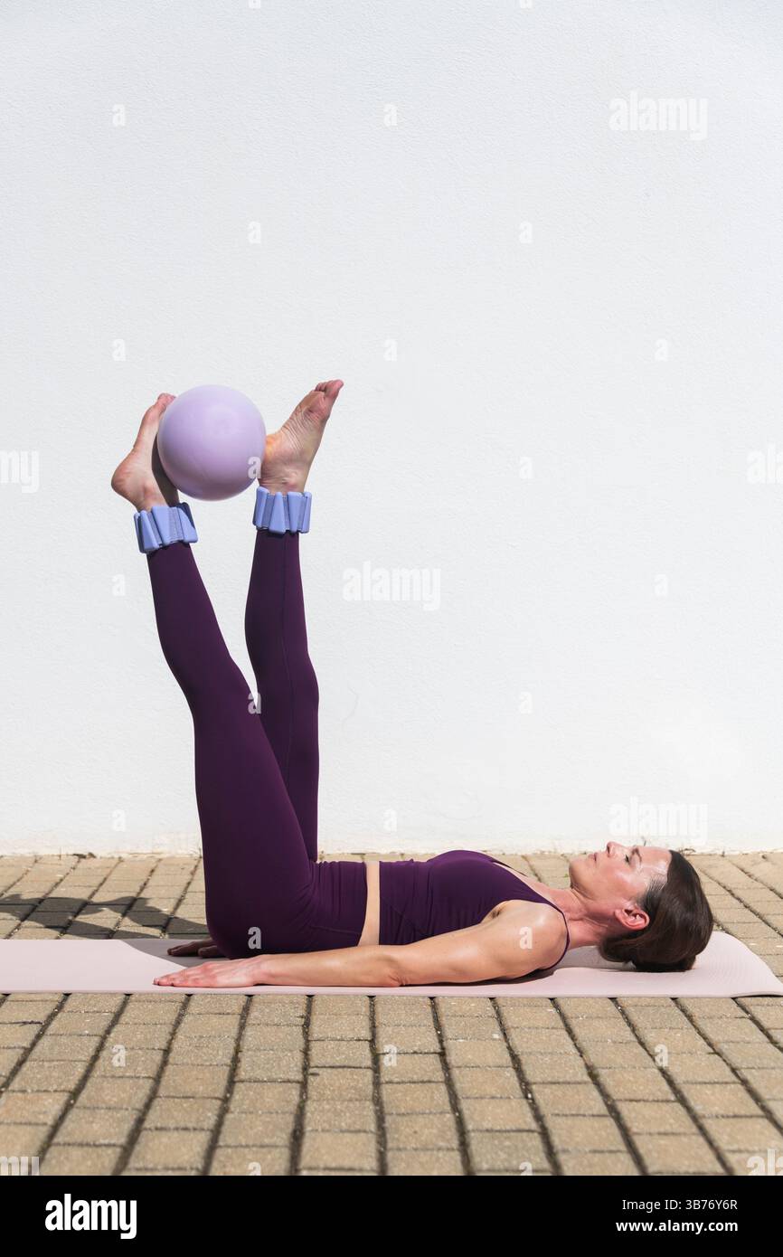 femme en forme faisant des exercices de pilates avec une balle, les jambes levées Banque D'Images
