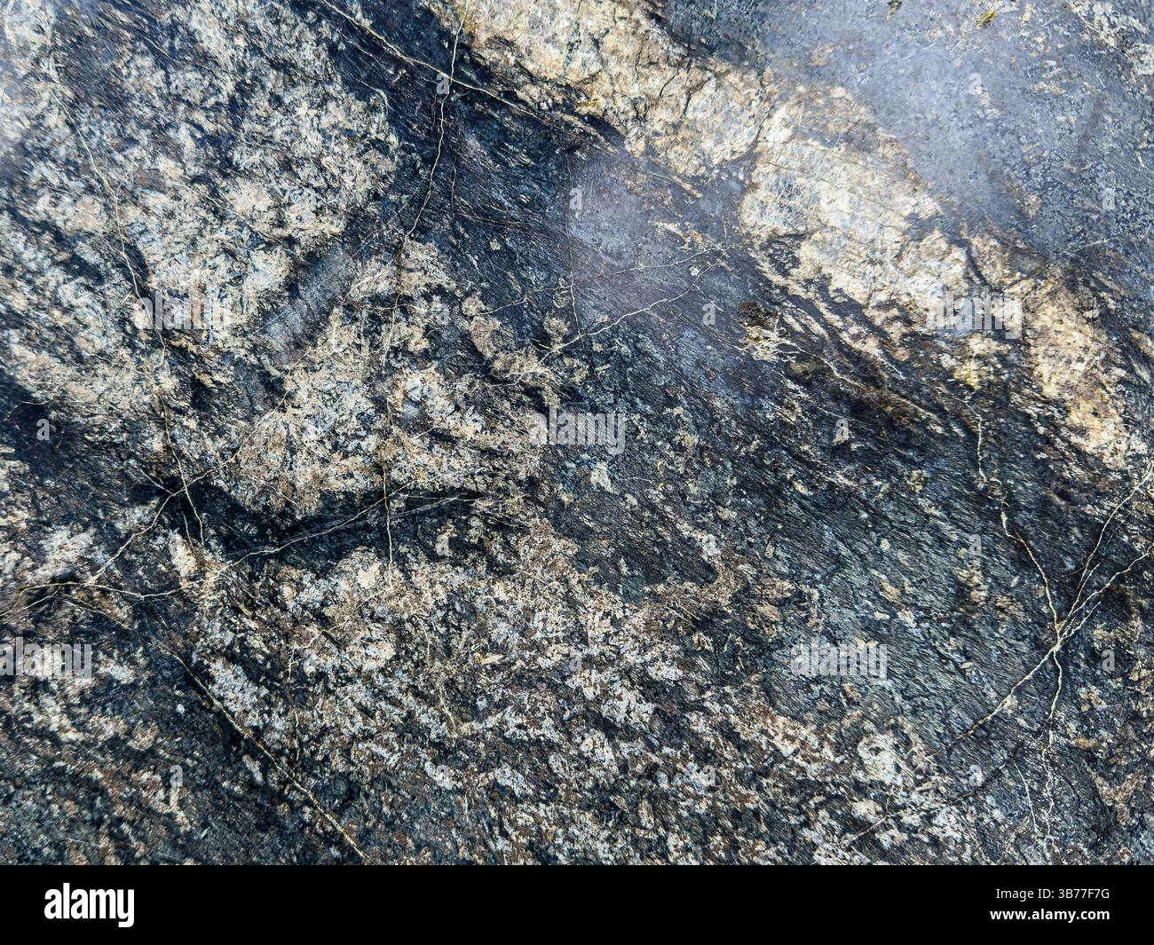 Une texture de pierre naturelle avec des fissures et de la mousse, montrant des détails rugueux et altérés. Banque D'Images